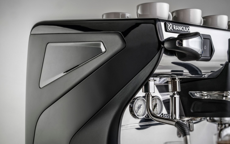 This image is a closeup front-side view of the Rancilio Classe 7 espresso machine steam wand, steam c-lever, gauges and side panels. 